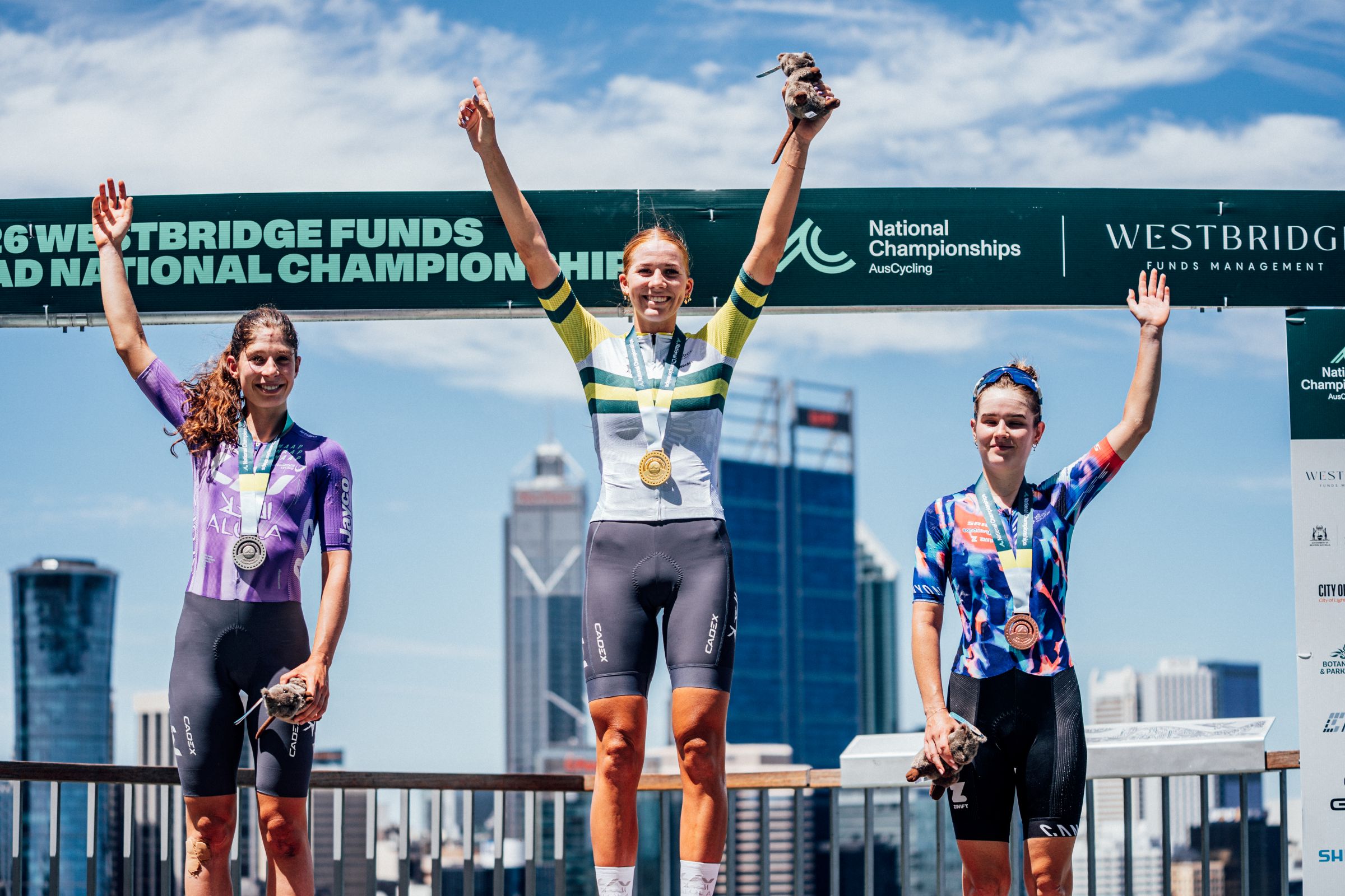 Mackenzie Coupland, Ruby Roseman-Gannon and Neve Bradbury on the podium of the elite women road race at the 2026 Westbridge Funds Road National Championships in Kings Park, Perth, Western Australia